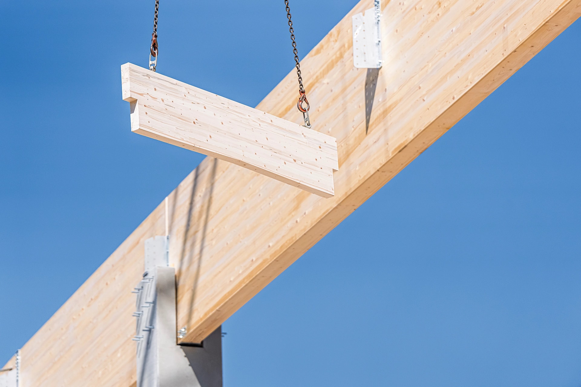 Porte-engins de X-Wood® chargé de poutres en lamellé-collé devant le chantier