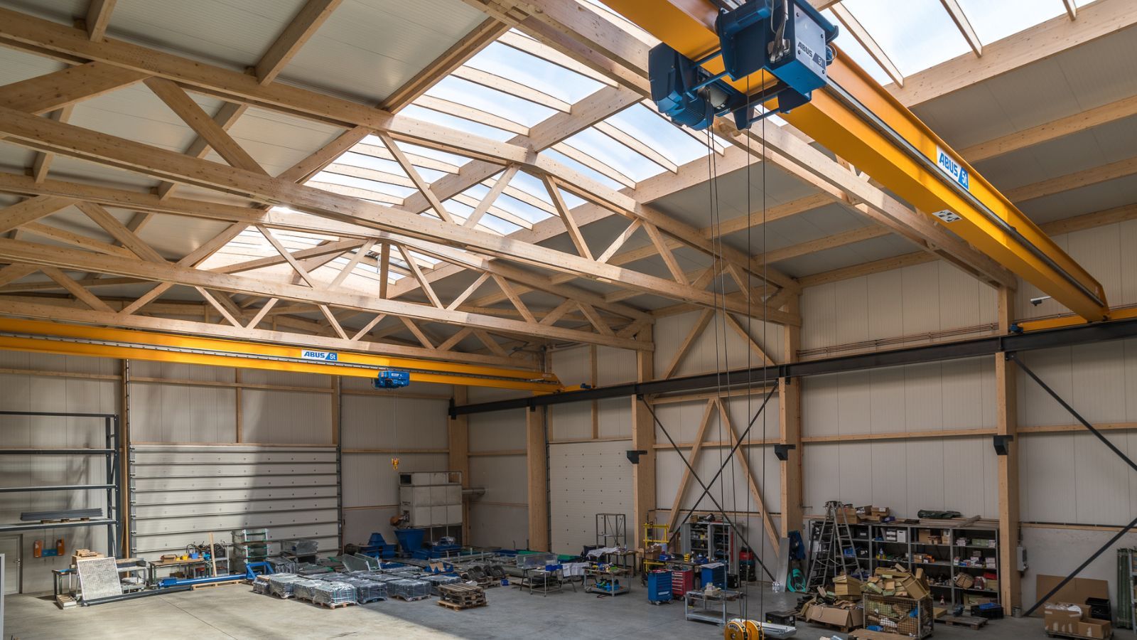 Innenansicht einer Produktionshalle mit Holztragwerk und Hallenkran unter dem Dach