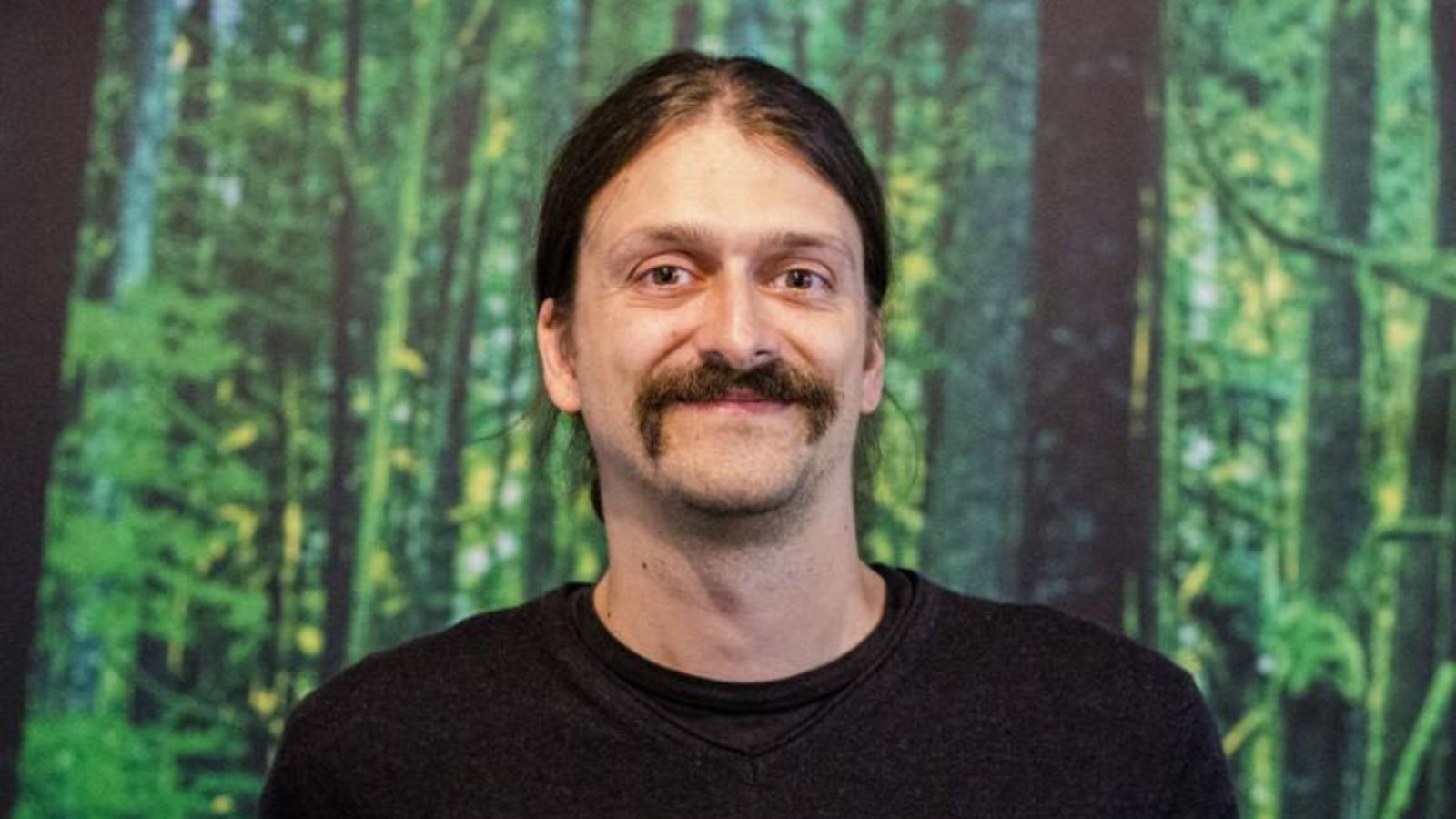 Porträt von Wolfgang Baum, Geschäftsführer von Fairventures Worldwide, vor einem grünen Waldhintergrund