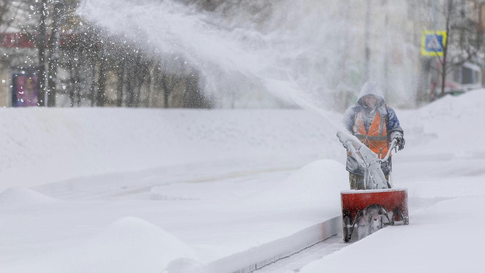 Person räumt mit Schneefräse eine große Schneemenge auf einer Fläche