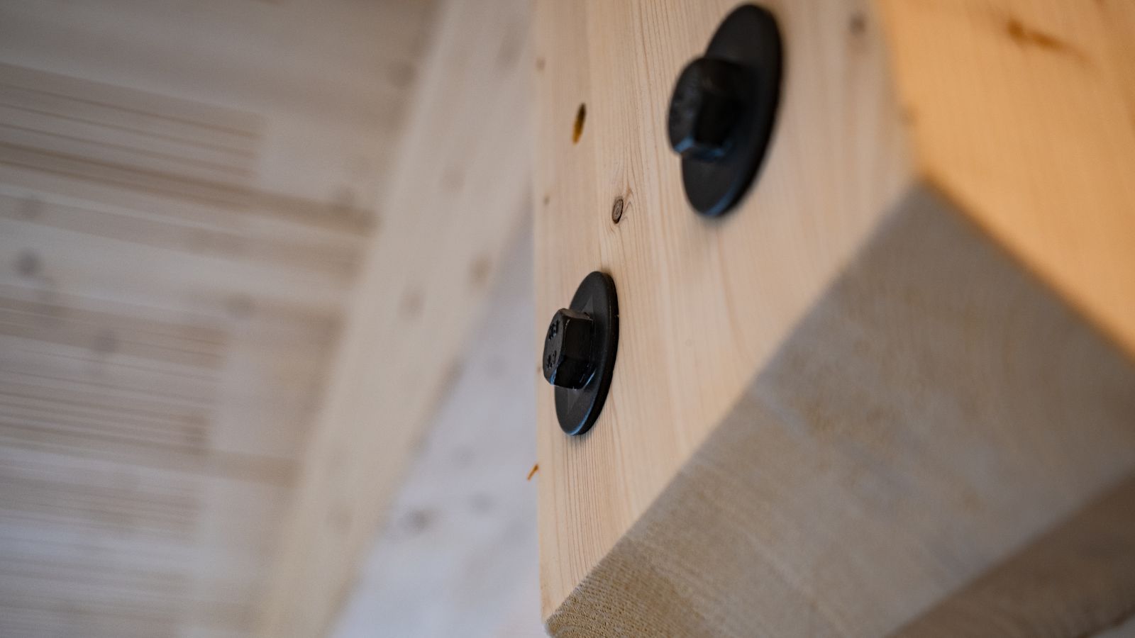Nahaufnahme einer lösbaren Holzverbindung mit schwarzer Schraube.