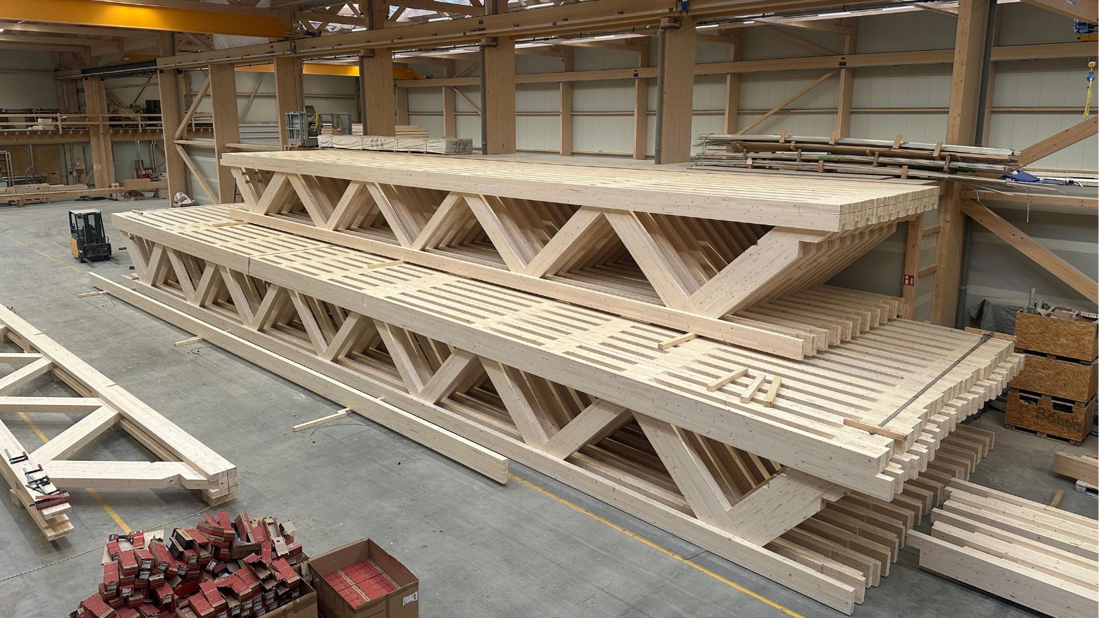 Gestapelte Holz-Fachwerkträger bei X-Cam, bereit für den Transport zur X-Wood® Baustelle