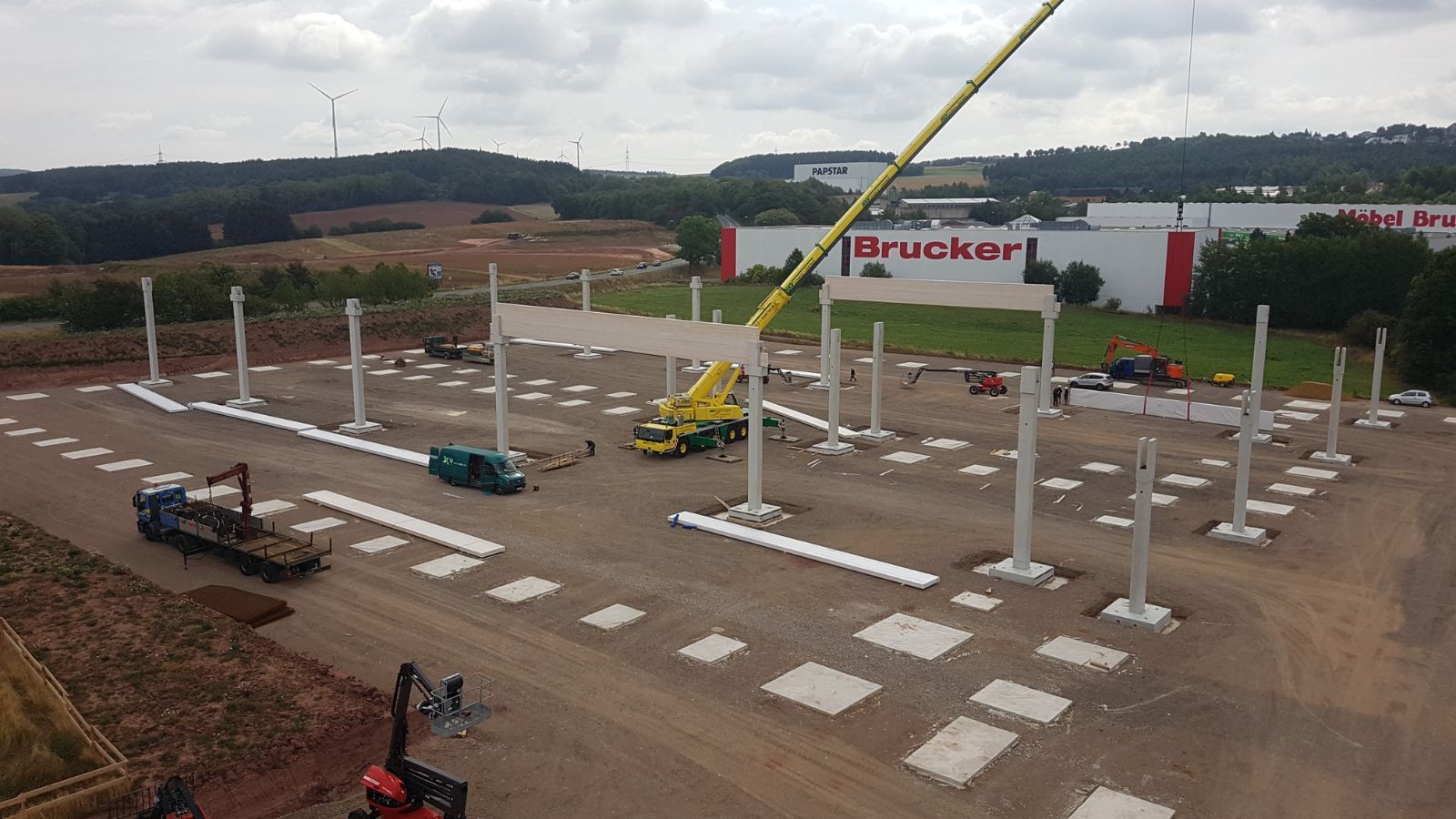 Aufbau von Betonstützen einer Industriehalle mit Autokran auf vorbereiteten Fundamenten