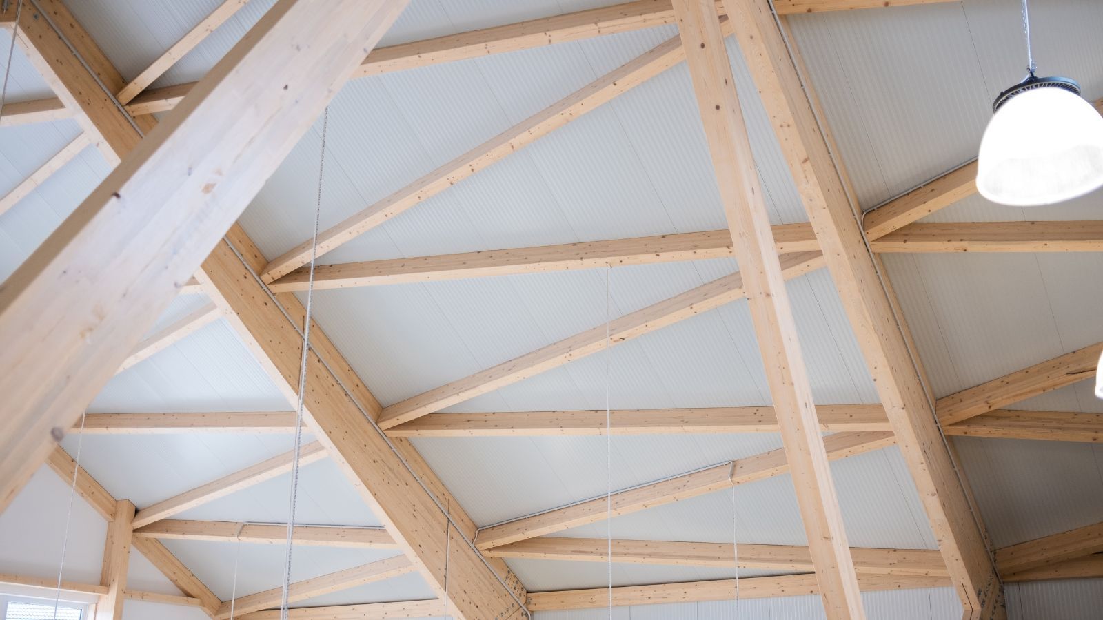 Sichtbare Holz-Dachkonstruktion mit schrägen Trägern und heller Verkleidung