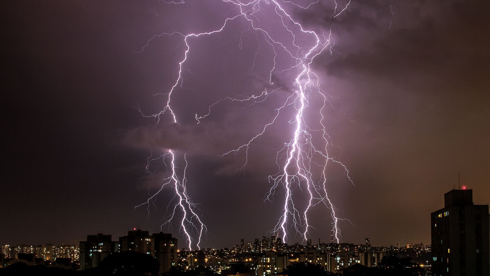 Mehrere Blitze über einer Stadt bei Nacht – Blitzgefahr auch in bebauten Gebieten.